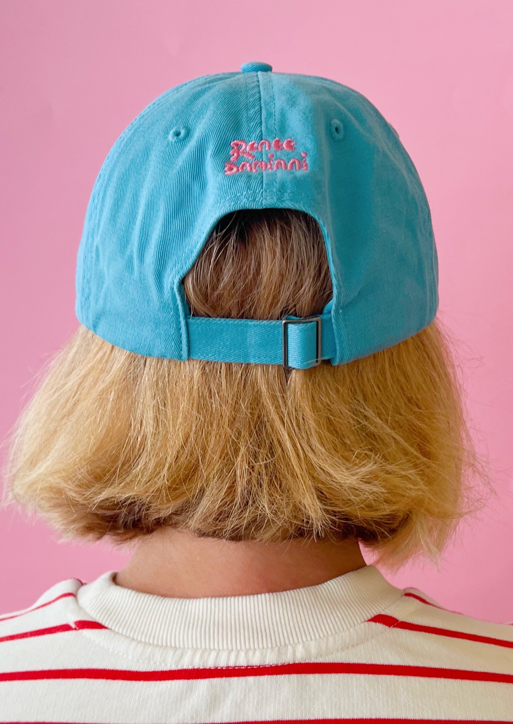 Person wearing a blue cap with text on a pink background