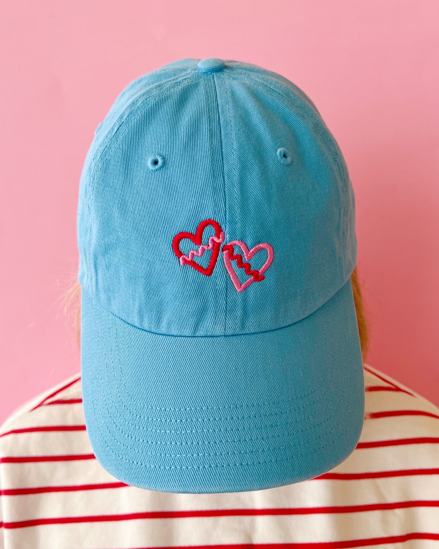 Blue cap with heart designs on a pink background