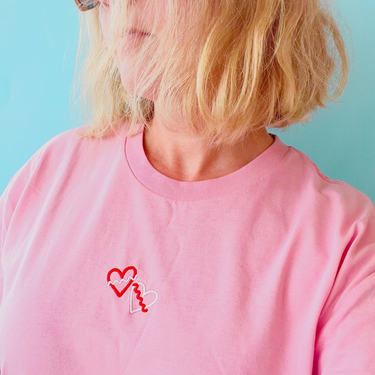 Person wearing a pink shirt with a heart and key design on a light blue background