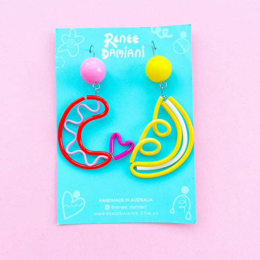 Front view of glossy hand-dyed plastic earrings: an orange and pink curled prawn beside a yellow and white lemon wedge.